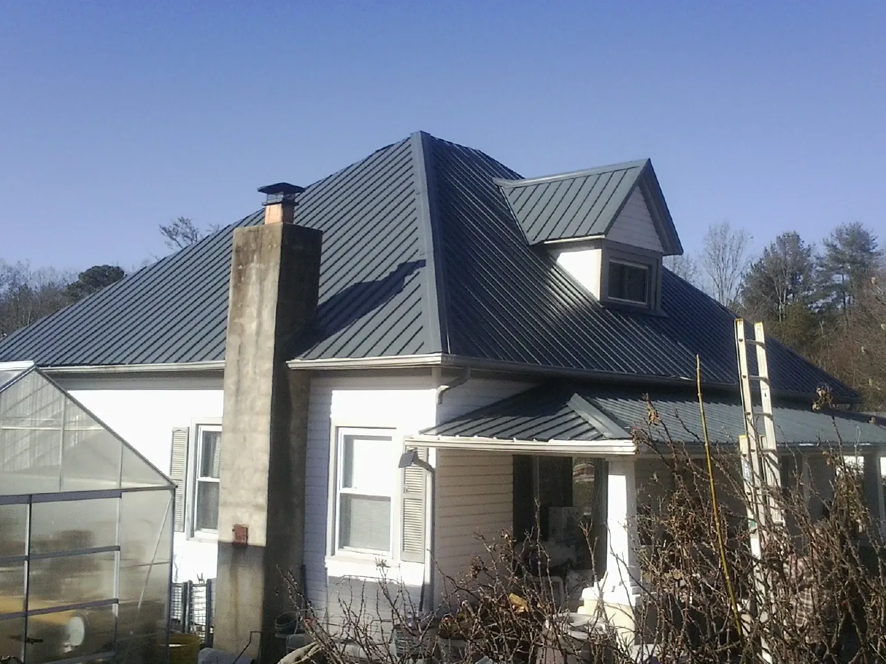 Dark blue standing seam metal roof on a white farmhouse with dormer — Slate & Tile Roof Repair by Roofing Brothers in Paragon