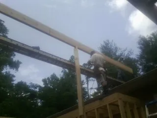 Carpenter setting a ridge beam over a new addition frame in Paragon