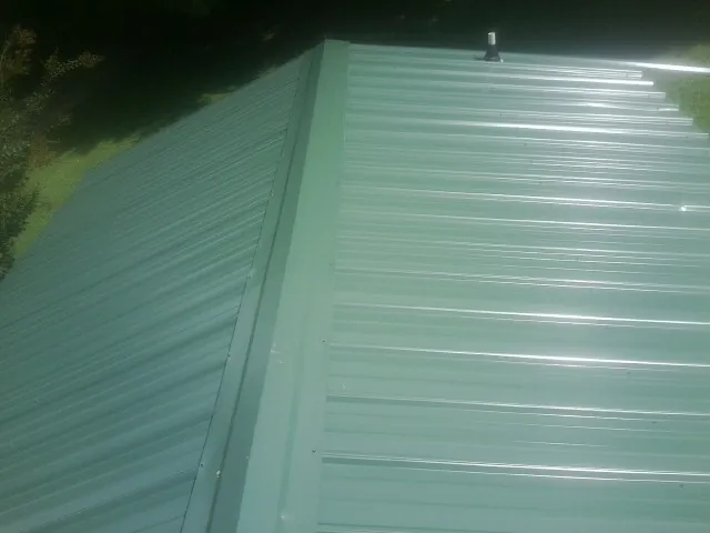 New green metal panels meeting at the ridge of a roof — Flat Roof Repair work by our crew in Paragon