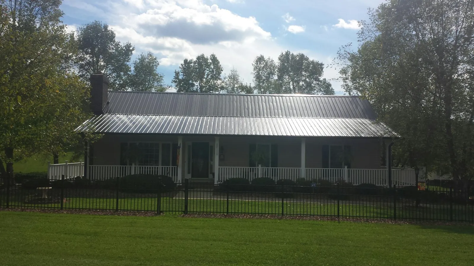 Gray metal roof on a brick ranch with a full width front porch — Gutter Guard Installation work by our crew in Paragon