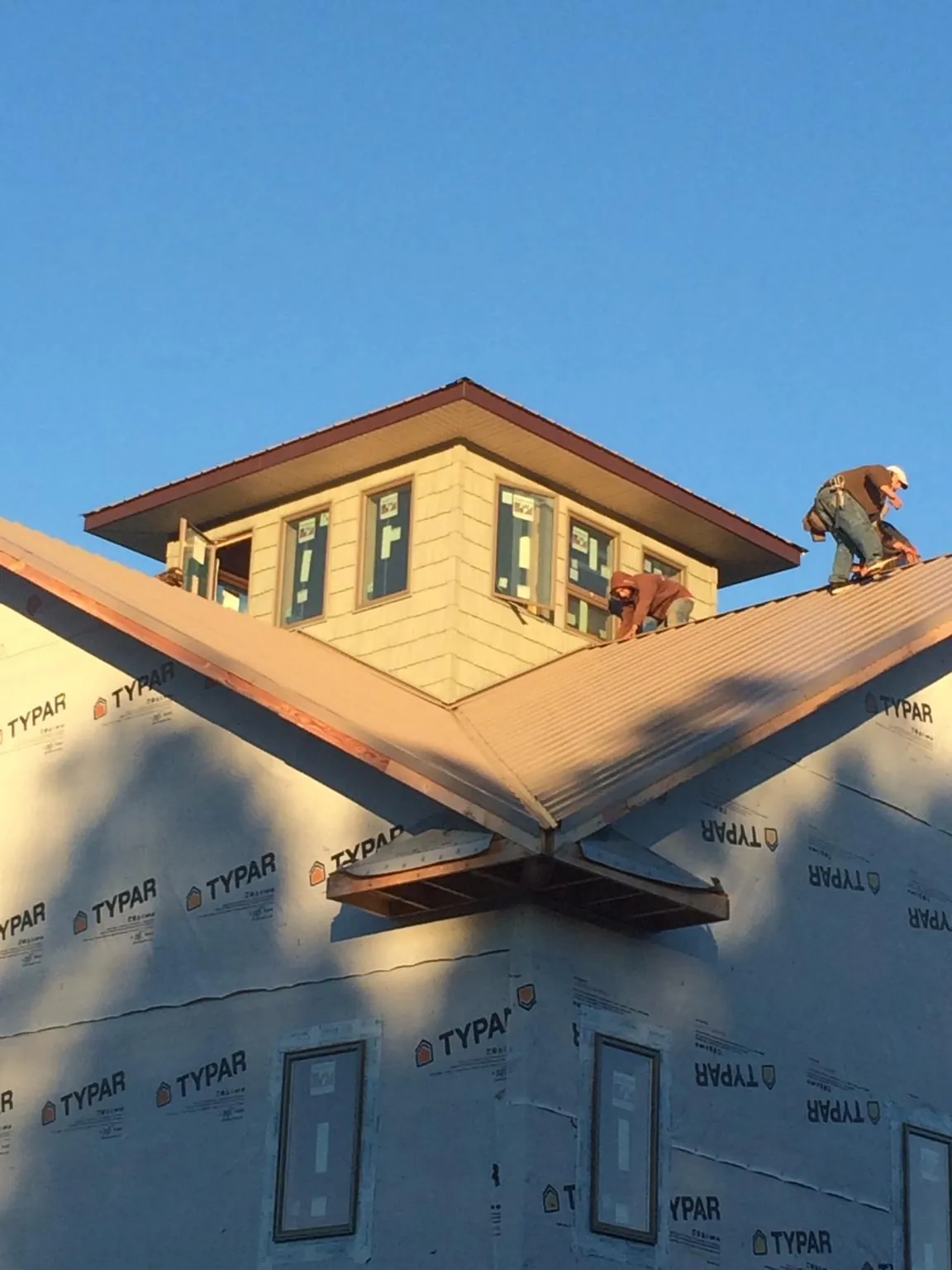 Roofers working around a rooftop cupola on a new metal roof at sunset — Roof Waterproofing in Paragon by Roofing Brothers